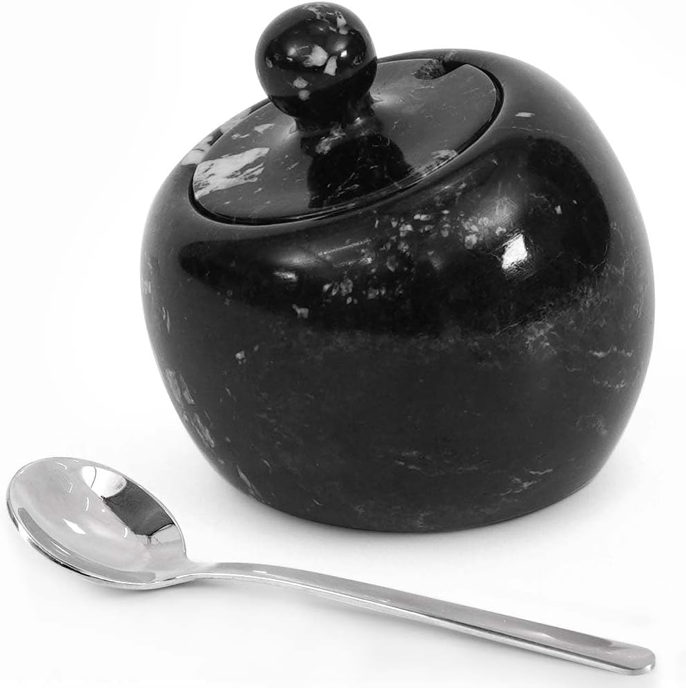 Black marble sugar bowl with a lid and a silver spoon on a white background