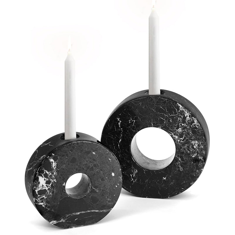 Two black marble candle holders with white candles on a white background