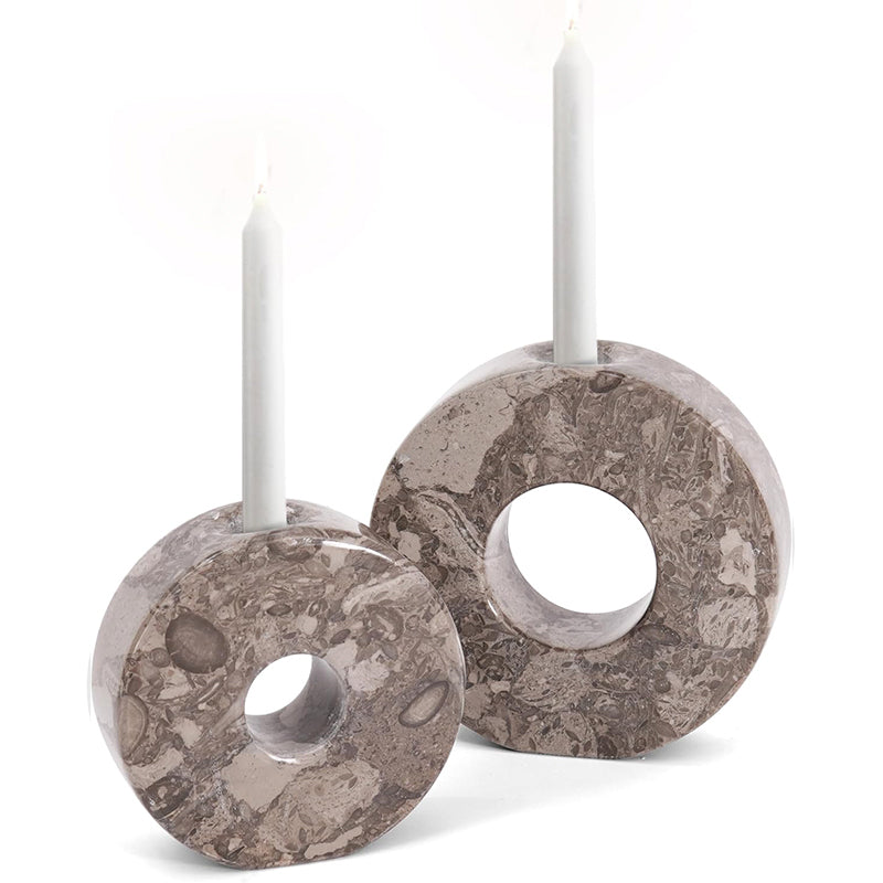 Two marble-patterned candle holders with white candles on a white background