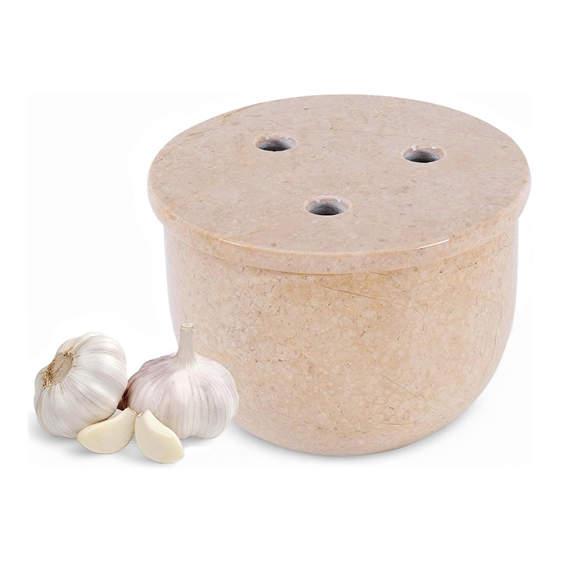 Beige stone garlic press with two cloves of garlic on a white background