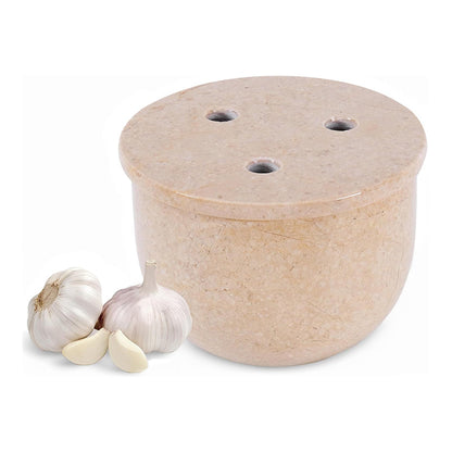 Beige stone garlic press with two cloves of garlic on a white background