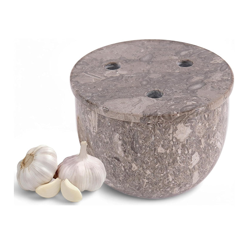 Marble garlic press with two cloves of garlic on a white background