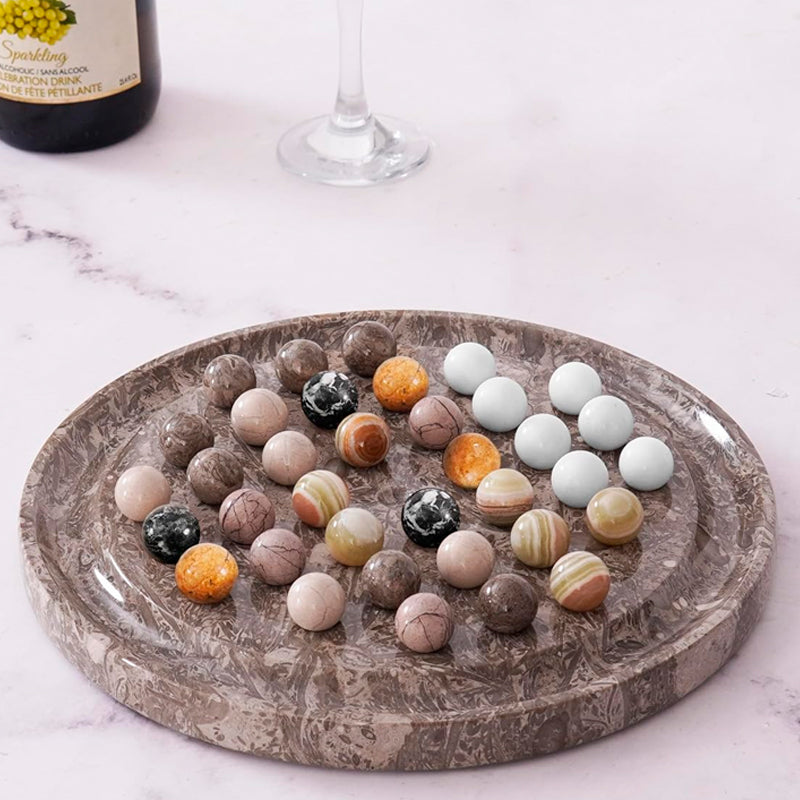 Decorative stone balls on a marble tray with a bottle and glass in the background.