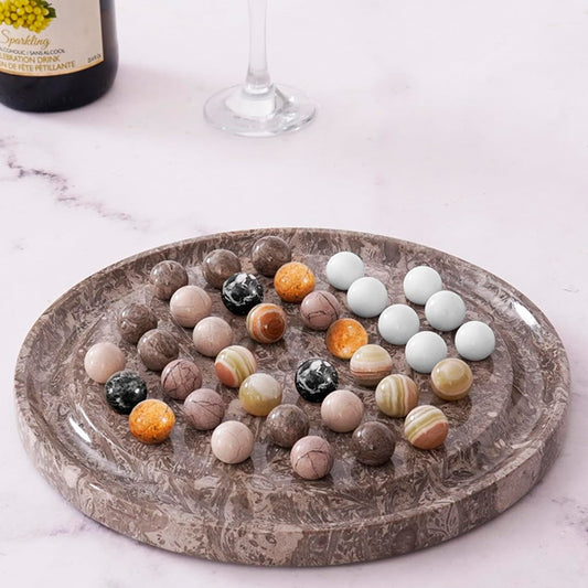 Decorative stone balls on a marble tray with a bottle and glass in the background.