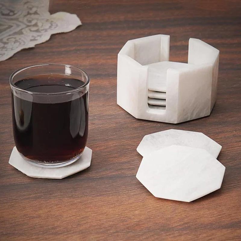 A set of marble star-shaped coasters with one holder, displayed on a wooden surface, with one coaster being used to hold a glass of liquid.