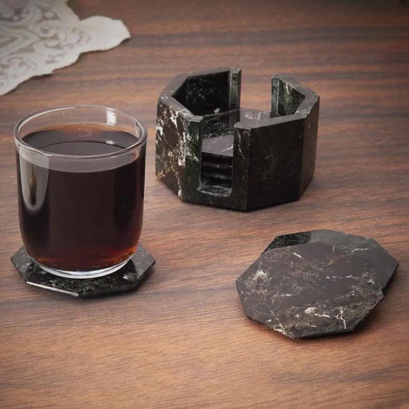A set of marble star-shaped coasters with one holder, displayed on a wooden surface, with one coaster being used to hold a glass of liquid.