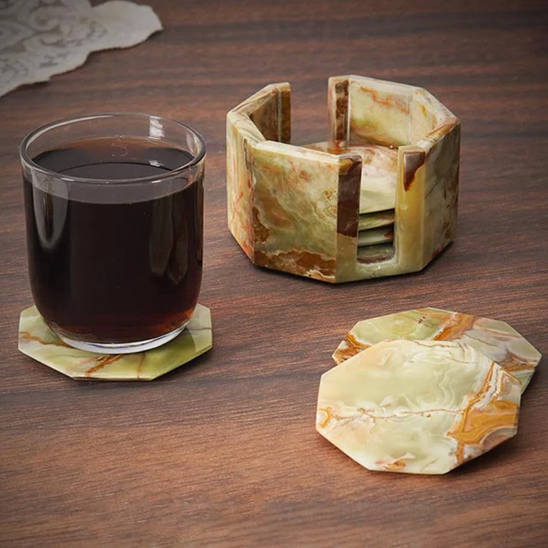 A set of marble star-shaped coasters with one holder, displayed on a wooden surface, with one coaster being used to hold a glass of liquid.
