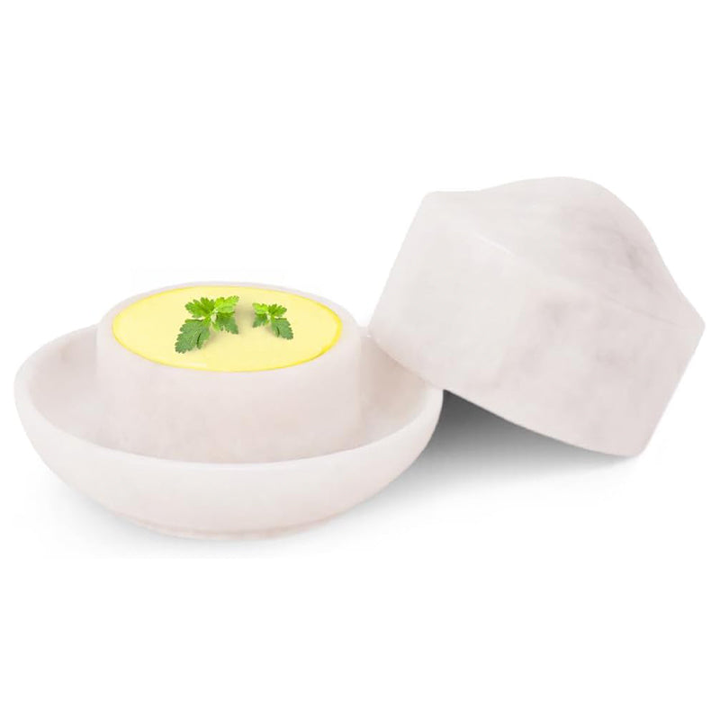 White ceramic egg holder with a cracked open egg containing a yellow yolk and green herbs on a white background