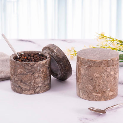Marble-textured spice containers on a marble surface with a blurred background