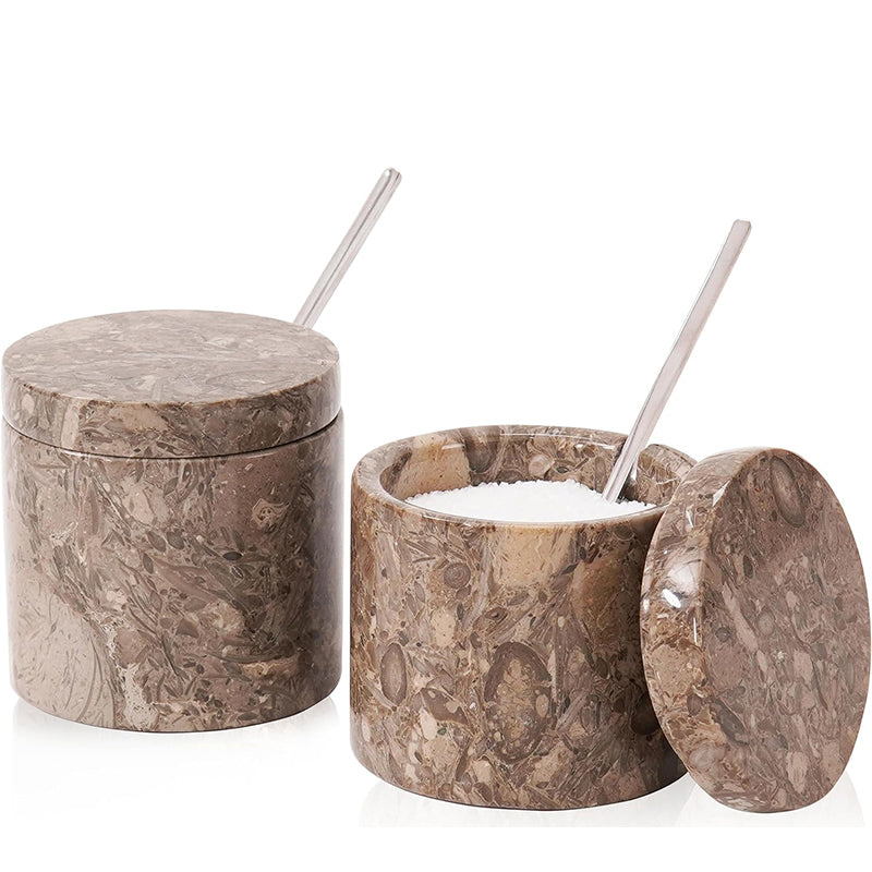 Marble-textured salt shaker with lid and spoon on a white background