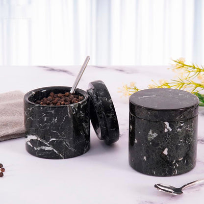 Black marble-textured spice jars on a light surface with a blurred background